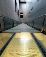 Perforated metal flooring on walkway leading around new exhibition tower, NGV International